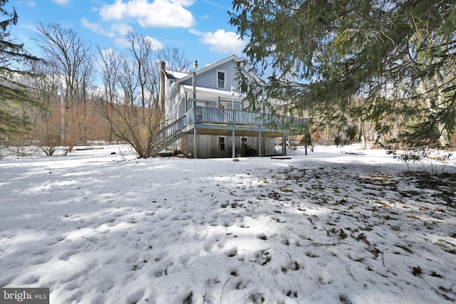 snow covered rear of property with a deck