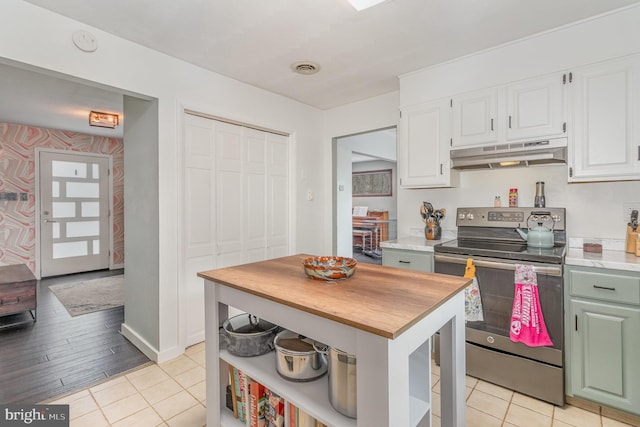 kitchen with light tile patterned flooring, stainless steel electric range oven, and white cabinets