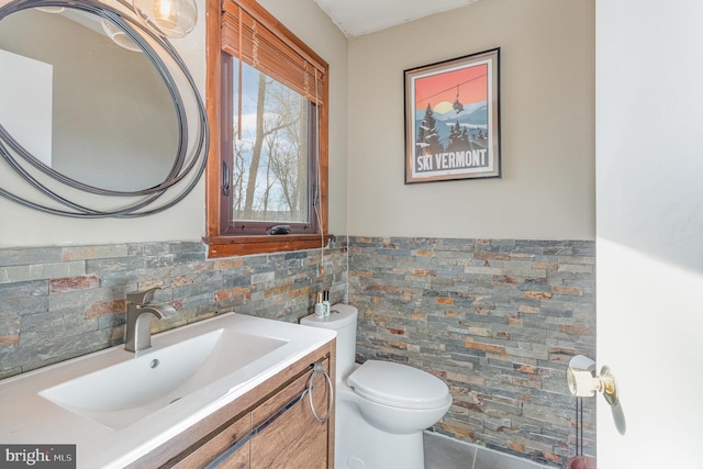 bathroom featuring vanity, tile walls, and toilet