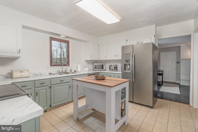 kitchen with sink, appliances with stainless steel finishes, white cabinetry, a center island, and light tile patterned flooring