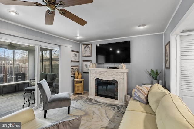 living room with crown molding, ceiling fan, and a premium fireplace