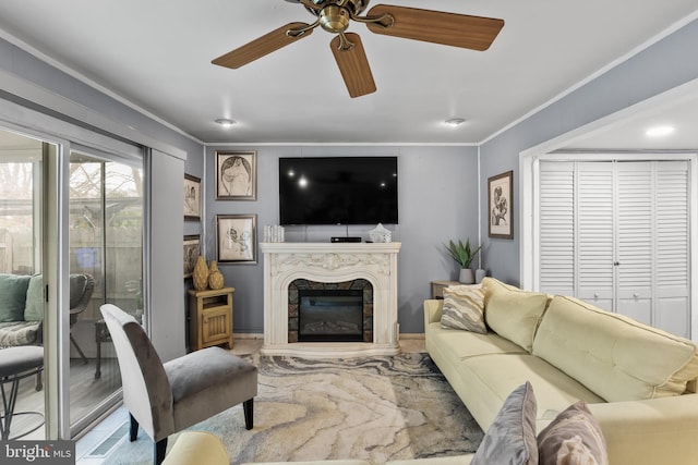 living room with crown molding, a fireplace, and ceiling fan