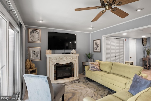 living room featuring a premium fireplace, ornamental molding, and ceiling fan