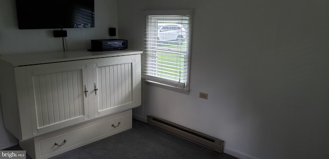 interior space with a baseboard heating unit and dark carpet