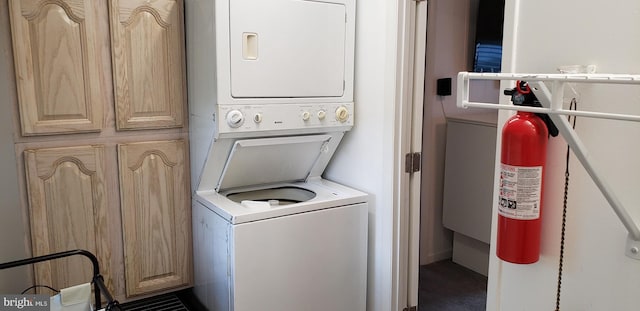 laundry room featuring cabinets and stacked washer and clothes dryer