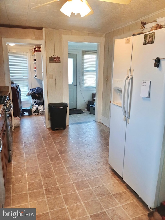 kitchen with wooden walls, stainless steel range with gas stovetop, and white fridge with ice dispenser