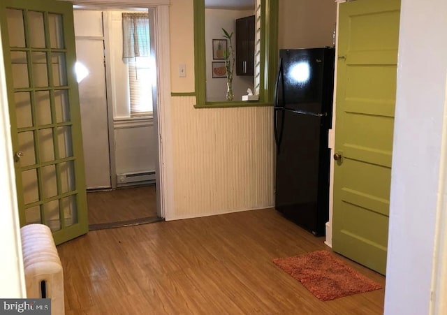 kitchen with black refrigerator, radiator heating unit, hardwood / wood-style flooring, and a baseboard heating unit