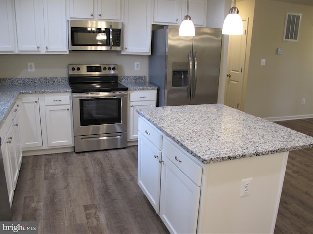 kitchen with appliances with stainless steel finishes, dark hardwood / wood-style floors, white cabinetry, hanging light fixtures, and light stone countertops