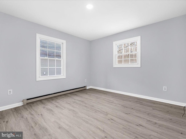 unfurnished room featuring light hardwood / wood-style flooring, a healthy amount of sunlight, and baseboard heating