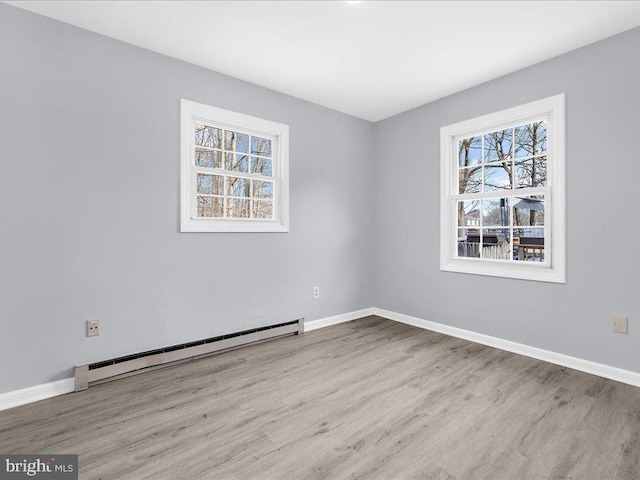 empty room with baseboard heating and light hardwood / wood-style floors