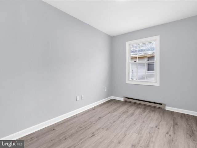 empty room featuring baseboard heating and light hardwood / wood-style flooring