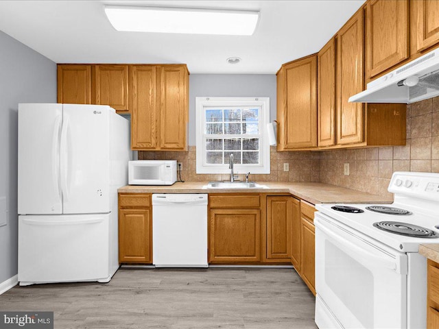 kitchen with sink, decorative backsplash, white appliances, and light wood-type flooring