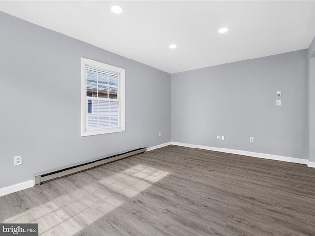 empty room with hardwood / wood-style floors and baseboard heating