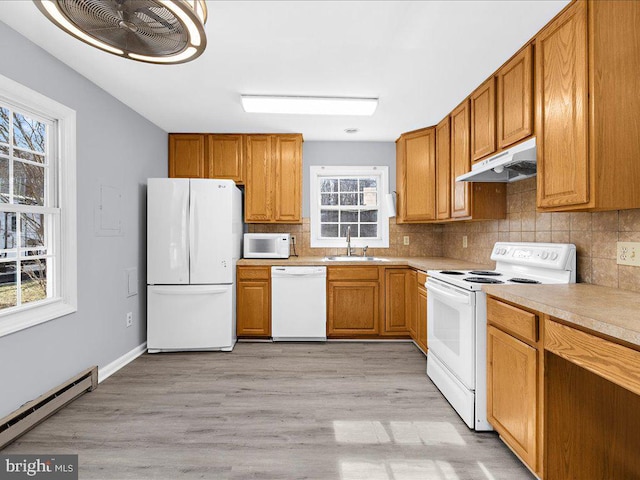 kitchen with sink, backsplash, white appliances, baseboard heating, and light wood-type flooring