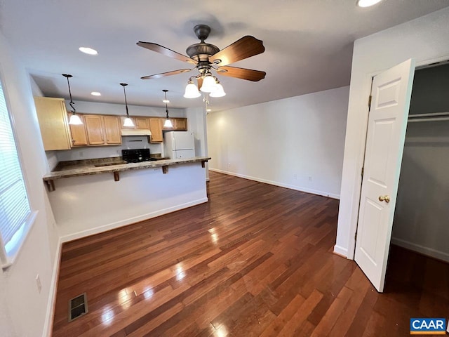 kitchen featuring hanging light fixtures, a kitchen breakfast bar, white refrigerator, black electric range, and kitchen peninsula