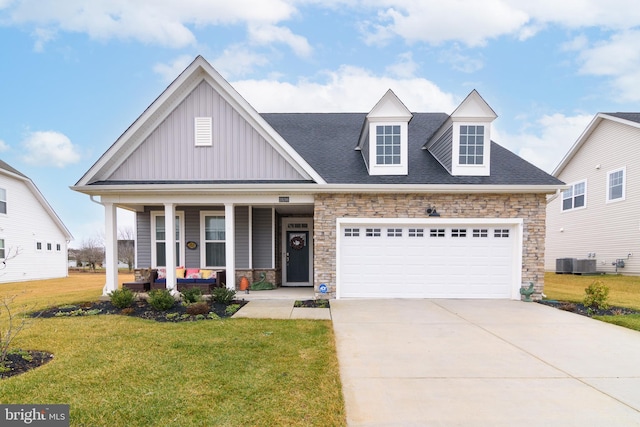 view of front of home featuring a garage, a porch, central air condition unit, and a front lawn