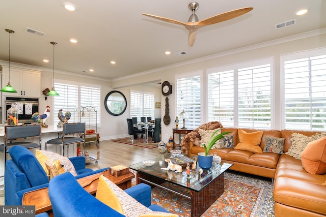 living room with ornamental molding, ceiling fan, and light hardwood / wood-style floors