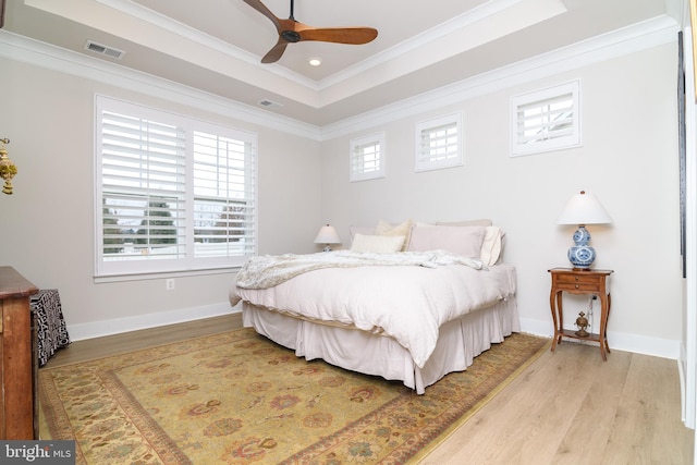 bedroom featuring crown molding, a tray ceiling, and light hardwood / wood-style floors