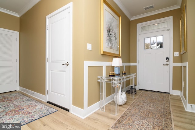 entryway with ornamental molding and light wood-type flooring