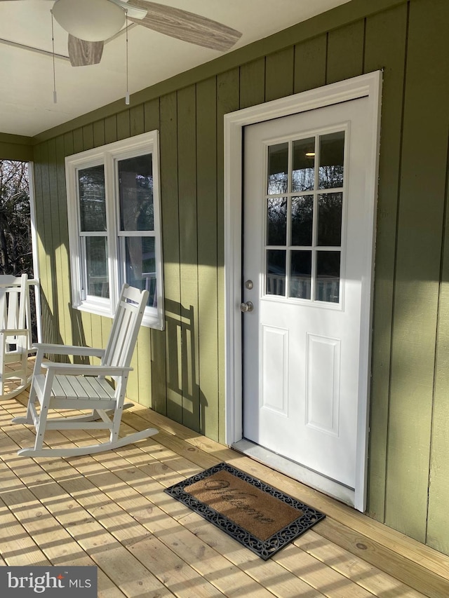 entrance to property featuring ceiling fan, a porch, and board and batten siding