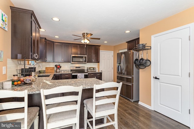 kitchen with sink, a breakfast bar, appliances with stainless steel finishes, backsplash, and light stone countertops