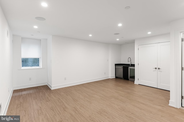 interior space with bar, beverage cooler, and light wood-type flooring