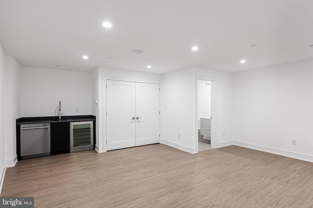 interior space featuring stainless steel dishwasher, beverage cooler, sink, and light hardwood / wood-style flooring