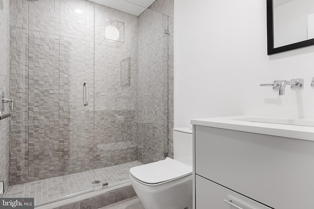 bathroom with vanity, a shower with door, and toilet