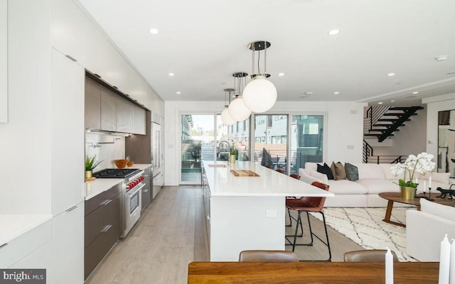 kitchen featuring sink, a kitchen breakfast bar, premium appliances, hanging light fixtures, and a center island with sink