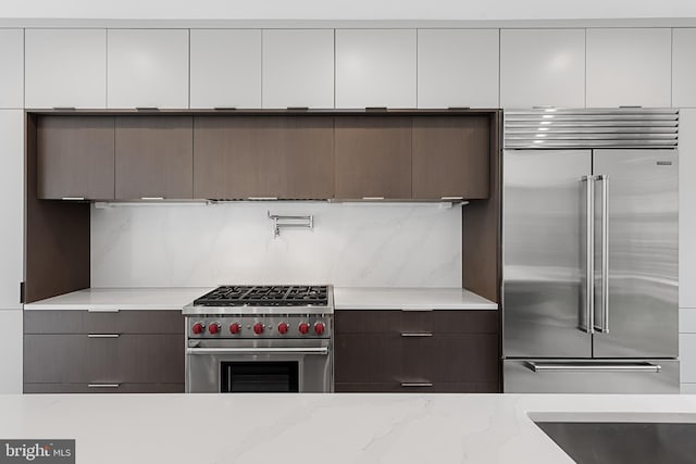 kitchen with white cabinetry, high quality appliances, and light stone countertops