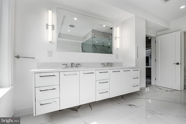 bathroom featuring a shower with door and vanity