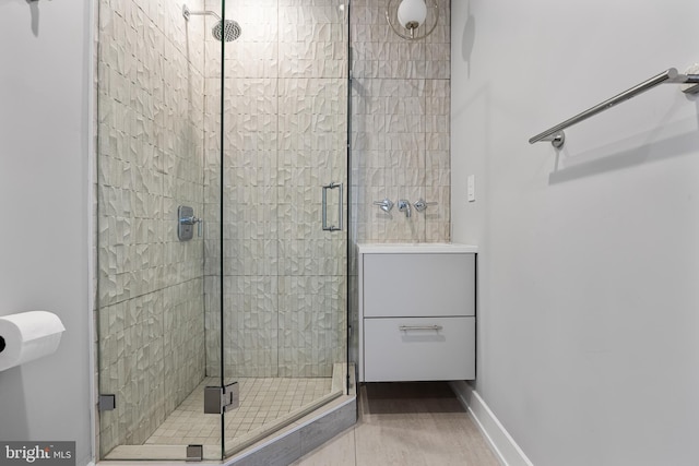 bathroom featuring a shower with shower door and sink