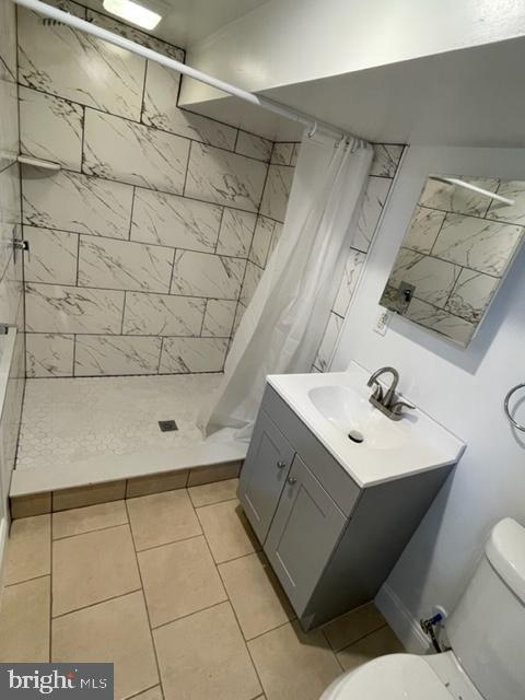 bathroom with walk in shower, vanity, and toilet