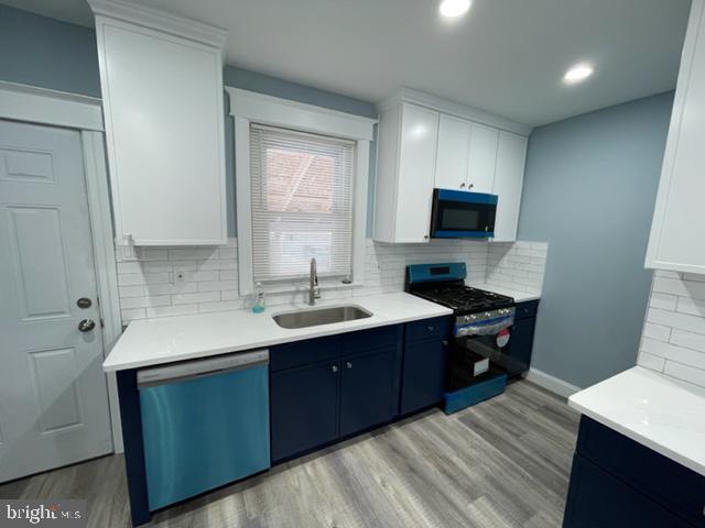 kitchen featuring appliances with stainless steel finishes, sink, white cabinets, and light hardwood / wood-style floors