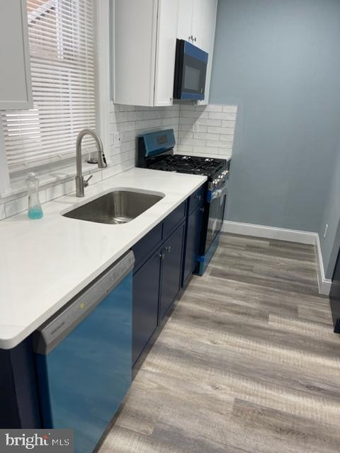 kitchen featuring sink, dishwasher, gas range oven, decorative backsplash, and white cabinets