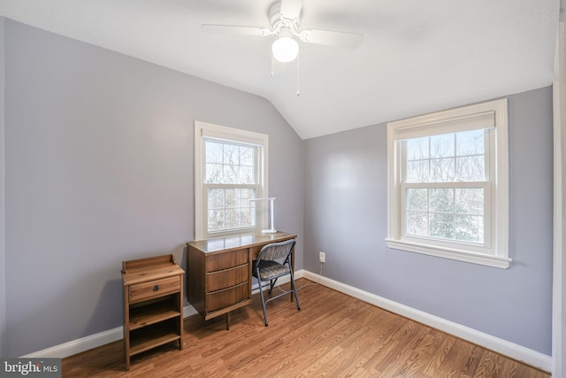 office space featuring a ceiling fan, light wood-type flooring, vaulted ceiling, and baseboards