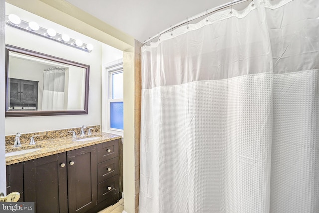 full bathroom with double vanity and a sink