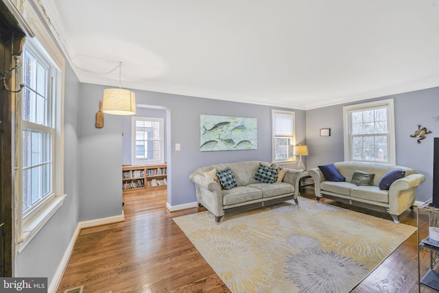 living room with baseboards, ornamental molding, and wood finished floors