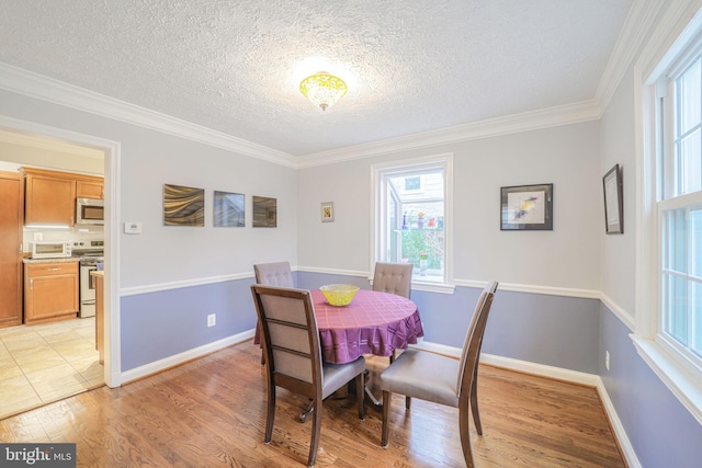 dining space with light wood-style floors, baseboards, and a textured ceiling