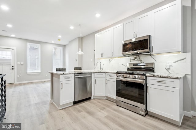 kitchen with white cabinetry, light stone counters, hanging light fixtures, kitchen peninsula, and stainless steel appliances