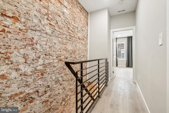 hall with brick wall and light hardwood / wood-style flooring