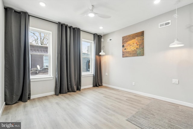 spare room with ceiling fan, plenty of natural light, and light wood-type flooring