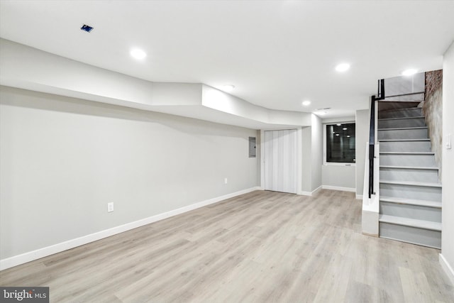 basement with electric panel and light hardwood / wood-style floors