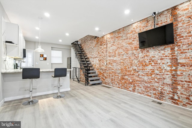 interior space with light hardwood / wood-style flooring and brick wall