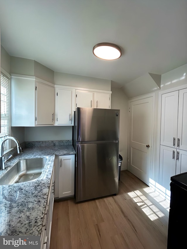 kitchen with white cabinetry, sink, stainless steel refrigerator, and light wood-type flooring