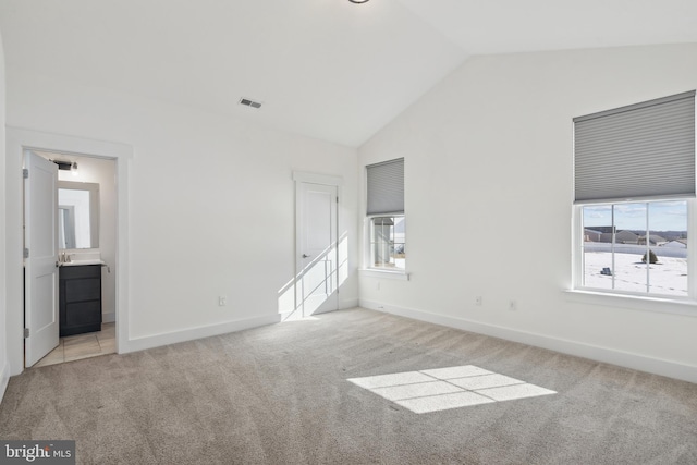 spare room with light carpet and vaulted ceiling