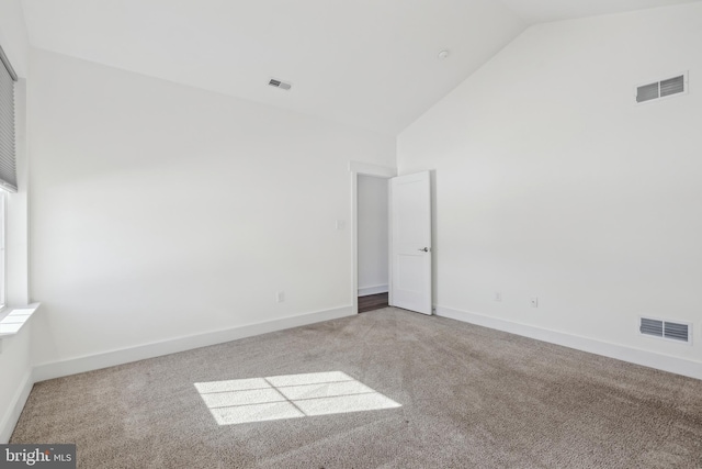 carpeted spare room featuring high vaulted ceiling