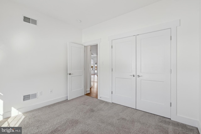 unfurnished bedroom with light colored carpet and a closet