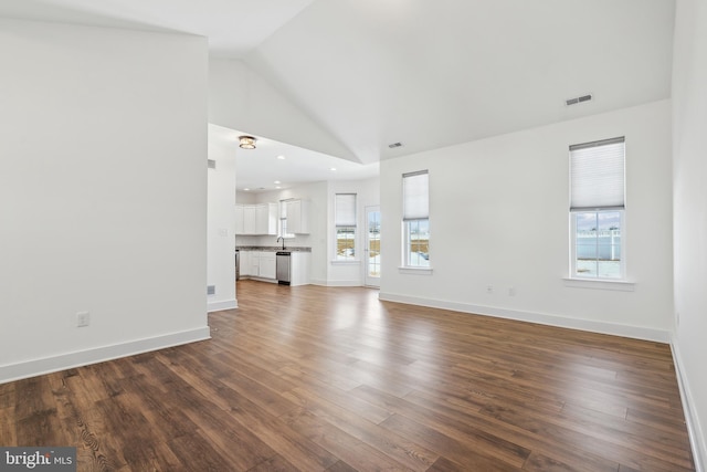 unfurnished living room with plenty of natural light, dark wood-type flooring, and high vaulted ceiling