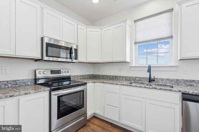 kitchen featuring stainless steel appliances, white cabinetry, sink, and light stone counters